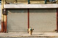 Shop exterior with closed shutters, street facing store, sidewalk and hydrant