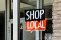 Shop local sign on storefront of small town business