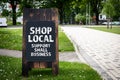 Shop Local. Support small business. Wooden billboard on the street, sunny day Royalty Free Stock Photo