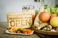 The shop open sign is placed on a wooden table with kimchi, Korean food and raw vegatable materials