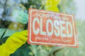 The shop owner hangs a sign to close the business in front of the door