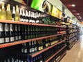 Shop shelves full with bottles of vine of different types stand in rows. Variety of alcoholic drinks