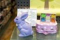 Shop showcase decorated for Easter. A blue wooden rabbit, a pink suitcase with polka dots, a shelf with colorful hares