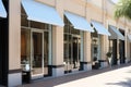 Shop storefront, white awnings, glass facade, outdoor decor.