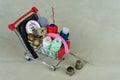 A shop trolley with threads, sewing accessories and buttons. The background is made of gray-beige fabric