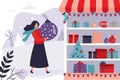 Shop window with Christmas decorations and gift boxes. Female character holding a big christmas tree toy. Concept of winter Royalty Free Stock Photo