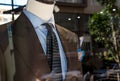 Shop window of mens tailor shop showing a mannequin in a brown tailored suit and blue tie Royalty Free Stock Photo