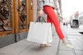 Shopaholic beautiful happy woman goes shopping in the city. Young girl in red pants and a lot of grey paper bags her Royalty Free Stock Photo