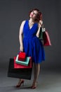 Shopaholic concept, young beautiful red-haired caucasian woman in blue dress posing in studio on gray background, professional Royalty Free Stock Photo