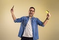 Shopaholic man with credit card and mobile phone screaming excitedly after winning rewards for online shopping. Young male Royalty Free Stock Photo