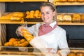 Shopkeeper at bakery putting loaf of bread into paper bag Royalty Free Stock Photo