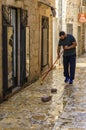 Shopkeeper cleaning the cobbled street by his shop in the medieval Old town in the Balkans in Budva, Montenegro Royalty Free Stock Photo