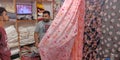 shopkeeper showing sari to gents customer at textiles showroom