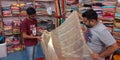 shopkeeper showing sari to male customer in showroom