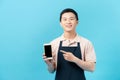 Shopman standing with apron uses a smart phone isolated on blue background Royalty Free Stock Photo