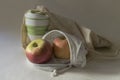 Shopper bag with collapsible silicone mug and apples in reusable fruit pouch