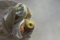 Shopper bag with collapsible silicone mug and apples in reusable fruit pouch