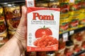 Shopper`s hand holding a package of Pomi brand italian chopped tomatoes