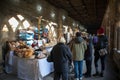 Shoppers customers at a bakery stall in a food market in cathedral cloisters showing people and stalls