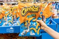 Shoppers hand holding a bag of cheetos brand puff cheese snacks