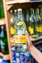 Shoppers hand holding a bottle of topo chico