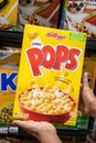 Shoppers hand holding a family size package of Kellogg`s brand corn pops cereal