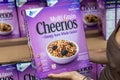 Shoppers hand holding a family size package of Multi grain cheerios brand cereals