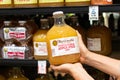 Shoppers hand holding a glass bottle of Martinelli`s brand 100% unfiltered apple juice