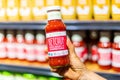 Shoppers hand holding a jar of Primal kitchen brand organic unsweetened ketchup