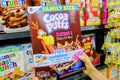 Shoppers hand holding a package of General Mills Brand Cocoa Puffs Flavored frosted corn puffs cereal for sale Royalty Free Stock Photo