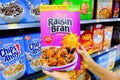 Shoppers hand holding a package Kellogg`s Brand Raisin bran flakes cereal for sale Royalty Free Stock Photo