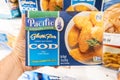 Shoppers hand holding a package of Pacific brand crispy battered Cod fish