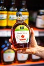 Shoppers hand holding a plastic bear jar of 365 whole foods brand of organic Grade A Maple syrup