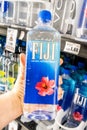 Shoppers hand holding a plastic bottle of Fiji brand natural artesian water