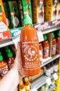 Shoppers hand holding a Plastic bottle of Huy Fong Food Sriracha hot chili sauce