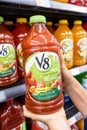 Shoppers hand holding a plastic bottle of V8 brand 100% vegetables juice