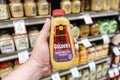 Shoppers hand holding a plastic container of Gulden`s brand spicy brown mustard