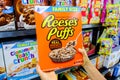 Shoppers hands holding a Package of General Mills Brand Reese`s puffs sweet and crunchy corn puffs made with peanut butter for