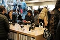 Shoppers and members of the public seen in a well-known retail store, trying headphones and other related accessories.