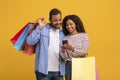 Shopping App. African American Couple Holding Shopper Bags And Using Smartphone Royalty Free Stock Photo