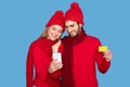 Shopping App. Happy Couple Wearing Winter Hats Using Smartphone And Credit Card Royalty Free Stock Photo