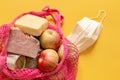 A shopping bag with basic food during quarantine and a protective mask nearby close up Royalty Free Stock Photo