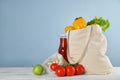 Shopping bag with fresh vegetables and other products on white wooden table against blue background, space for text Royalty Free Stock Photo
