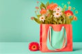 Shopping bag in living coral color with flowers bunch standing on table at turquoise wall background