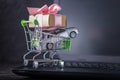 Shopping basket with car and gift box on laptop keyboard on dark background. Online shopping vehicles on the Internet Royalty Free Stock Photo