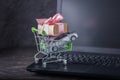 Shopping basket with car and gift box on laptop keyboard on dark background. Online shopping vehicles on the Internet Royalty Free Stock Photo