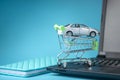 Shopping basket with car on laptop keyboard on blue background. Concept of online shopping vehicles on the Internet Royalty Free Stock Photo