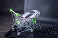 Shopping basket with car on laptop keyboard on dark background. Concept of online shopping vehicles on the Internet Royalty Free Stock Photo