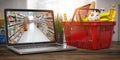 Shopping basket with food and laptop with shelf of supermarket or grocery shop on the screen. Online ordering and delivery food