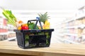 Shopping basket full of groceries in supermarket background